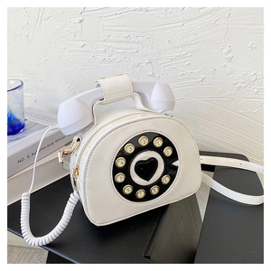 Detailed shot of a creative white vintage telephone-shaped crossbody bag with a heart dial