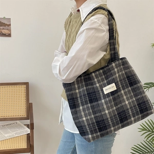 Detail of the large plaid canvas tote bag in a minimalist lifestyle setting with a model