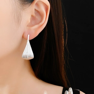 Close-up of silver leaf earrings with textured finish worn on a model's ear