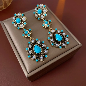 Close-up of vintage gold floral earrings with blue turquoise and small white beads