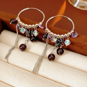 Détail de boucles d'oreilles vintage avec perles violettes et pampilles argentées