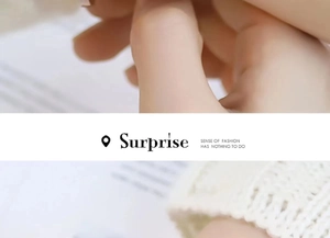 Close-up of minimalist gold ring held by hand featuring decorative Surprise typography