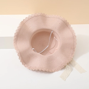 Elegant pink woven sun hat with delicate lace bow and wavy brim for summer beach use