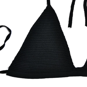 Dettaglio del top bikini in maglia nera con texture intrecciata e lacci sottili rifiniti