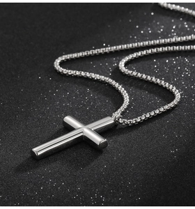Polished silver stainless steel cross pendant on a sleek box chain against a black background