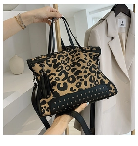 Detail of leopard print tote bag featuring black leather trim and decorative tassel charm