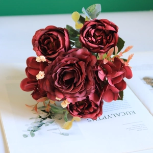 Detailed view of dark red faux roses and silk hydrangeas on an open magazine decor
