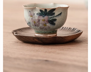 Vue macro d'une tasse à thé en céramique avec motif floral et soucoupe en bois