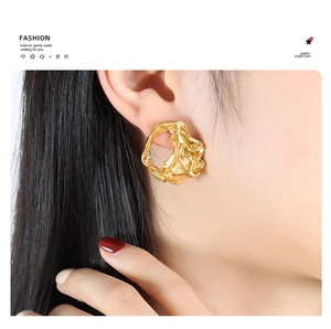 Detailed close-up of golden irregular hollow earrings with a molten metal texture