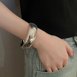 Detail of silver wide cuff bracelet with crocodile texture on a female model wrist