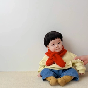 Close-up of baby red knitted scarf with cross-over design and soft warm texture