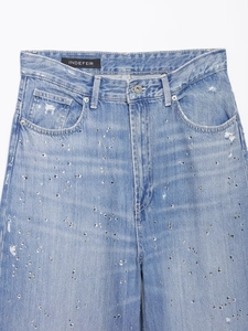 Détail du pantalon en jean bleu clair avec strass argentés et étiquette de marque INDEFEIR
