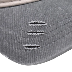 Detailed close-up of grey washed denim baseball cap brim with vintage distressed rips