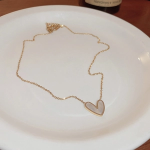 Detail of gold heart necklace with white mother-of-pearl shell pendant in a ceramic dish