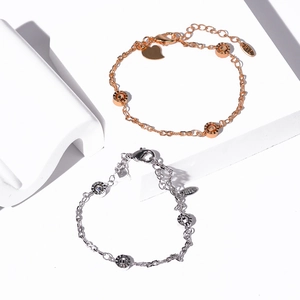 Detail of rose gold and silver butterfly bracelets with heart charms on geometric props