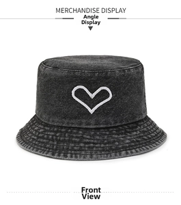 Detail of white heart embroidery on washed black denim bucket hat with fine stitching