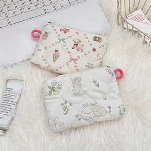 Close-up of quilted cosmetic pouches featuring cartoon sheep and rabbit patterns on plush background