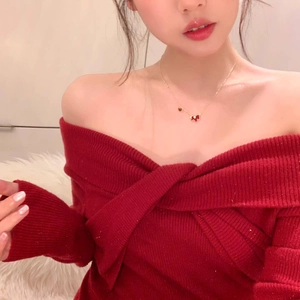 Close-up of elegant gold horse necklace on a red knit shoulder top with graceful neckline