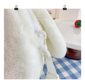 Detailed macro view of the zipper closure and white plastic buckle on the plush crossbody bag