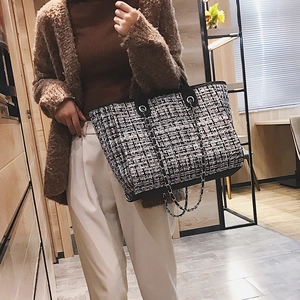 Fashionable black and white tweed tote bag with chain strap shown on model in a cafe