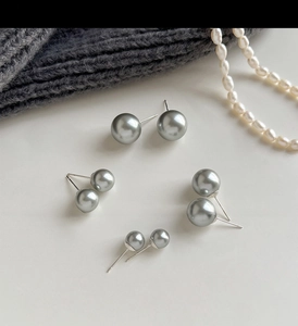 Detail view of grey pearl studs in four sizes with S925 silver needles on knit fabric