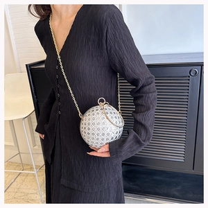 Detailed view of a silver spherical evening bag with rhinestones and gold chain strap