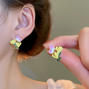 Close-up of yellow and purple tulip flower earrings with gold metal butterfly detail