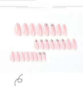 Close-up of almond nude pink press-on nails with glitter and rhinestone accents