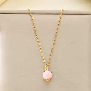 Close-up of a gold-plated necklace featuring a pink peach enamel pendant with green leaves