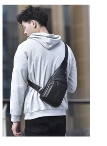 Outdoor shot of a black leather chest bag for men with adjustable straps on a male model