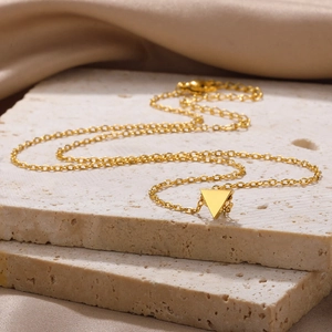 Macro shot of gold triangular pendant necklace on luxury satin with lobster clasp details
