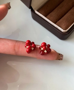 Detail shot of red berry stud earrings with gold plating and sparkling zircon accents