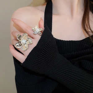 Detail view of a model wearing silver irregular flower rings with elegant white pearls
