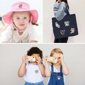 Cartoon cat embroidery patches shown on kids hats, black canvas bags and denim overalls