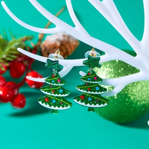 Detail of green acrylic Christmas tree earrings with glitter and colorful star accents