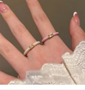 Macro view of minimalist enamel open rings with rectangular zircons on lace cuff background