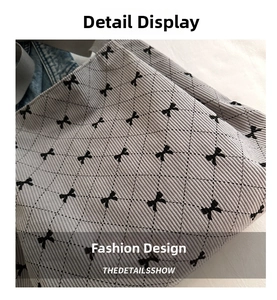 Detail of light gray corduroy tote with quilted diamonds and black bow patterns