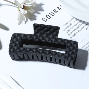 Detail shot of matte black geometric checkered hair claw clip on a minimalist background