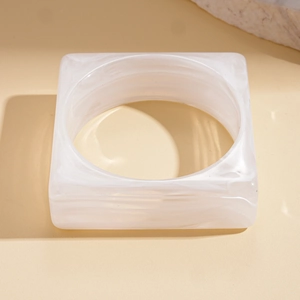 Close-up of white marble pattern on square acrylic bangle with minimalist geometric design