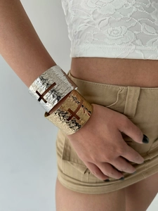 Detail of hammer-textured open bangles with cross cutout in gold and silver finish