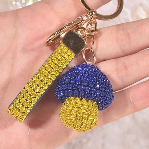 Close-up of mushroom keychain with blue and yellow rhinestones on a gold wrist strap