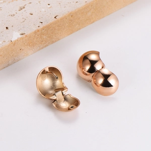 Polished gold spherical hoop earrings with hinge closure on a minimalist stone background