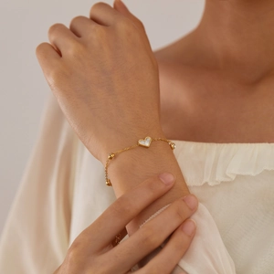 Elegant gold titanium bracelet featuring white heart shell pendant and zircon stones