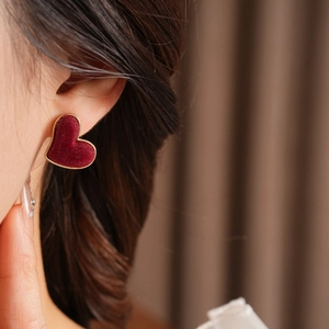 Close-up of red flocked heart earrings with gold trim on model ear for style