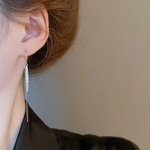 Detail of silver drop tassel earrings with zircon stones worn by a model in a side view