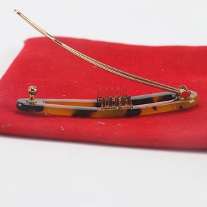 Detailed view of tortoiseshell resin hair clip on red velvet pouch with gold metal clasp
