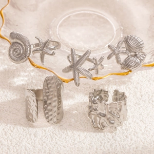Irregular silver starfish and seashell rings displayed on a golden glass plate