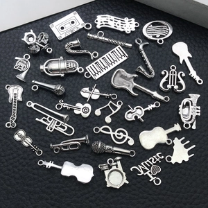 Variety of antique silver music instrument charms including guitar and violin on black background