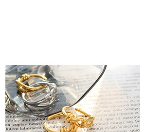Close-up of gold and silver knot rings with metallic texture on vintage background