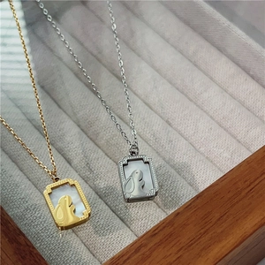 Close-up of gold and silver rabbit necklaces with white mother of pearl square pendants